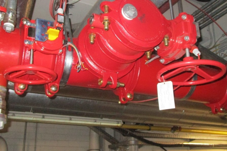 Zu sehen ist ein Teil einer Sprinklerleitung, ein Rohr in der Farbe Rot mit mehreren Ventilennur aus einer Ansicht direkt darunter.